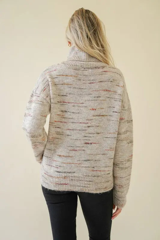 A female model showcasing a oatmeal textured turtleneck pullover sweater