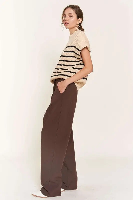 A woman modeling a beige striped sweater vest