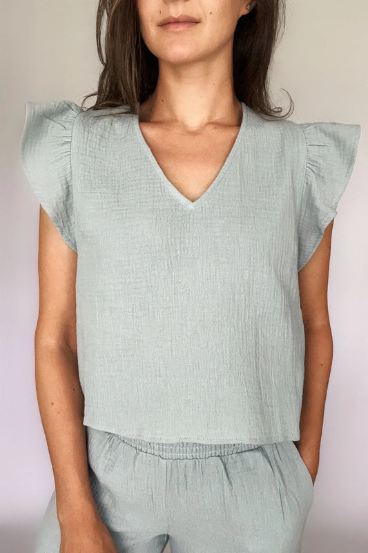 A woman modeling a sea blue cotton gauze ruffled sleeve top with matching pants