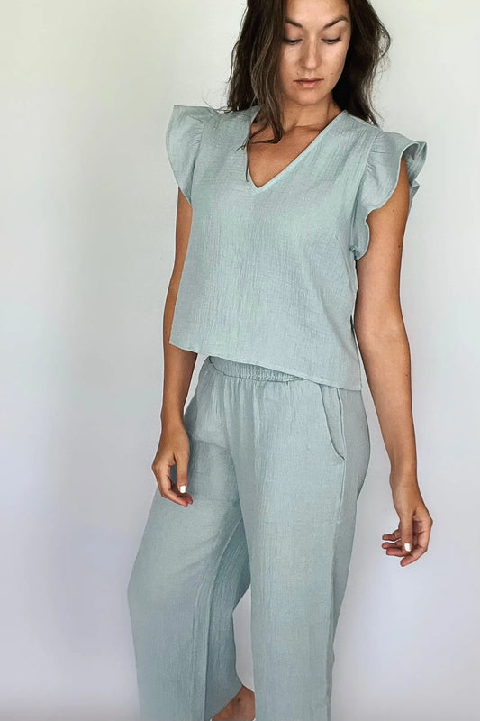 A woman modeling a sea blue cotton gauze ruffled sleeve top with matching pants