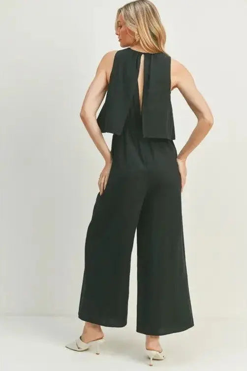 A female model showcasing a black wide-leg sleeveless jumpsuit