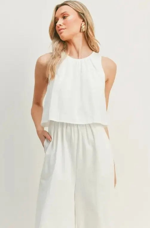 A woman modeling a white wide-leg sleeveless jumpsuit