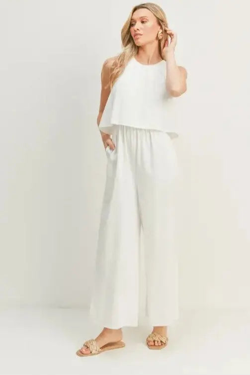A woman modeling a white wide-leg sleeveless jumpsuit