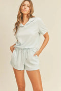 A female model wearing open collar polo and short terry cloth set