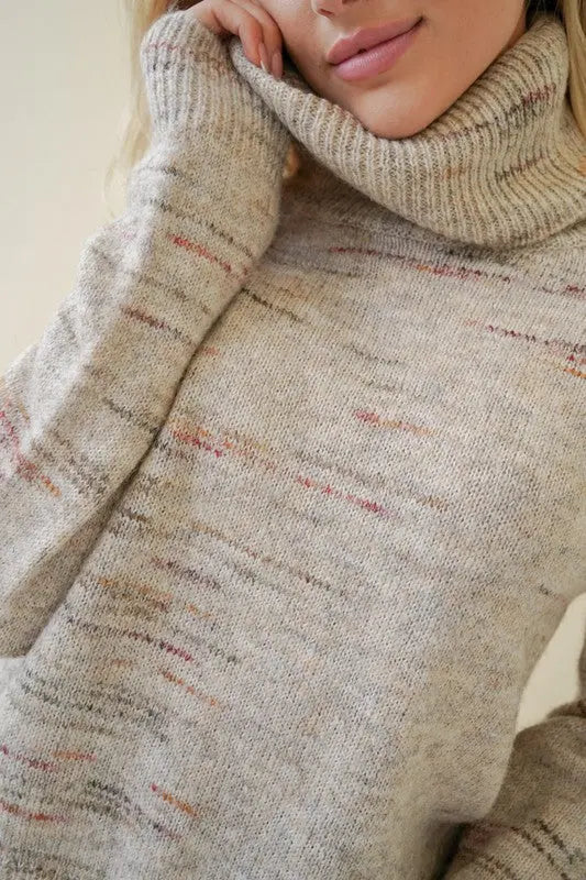 A female model showcasing a oatmeal textured turtleneck pullover sweater