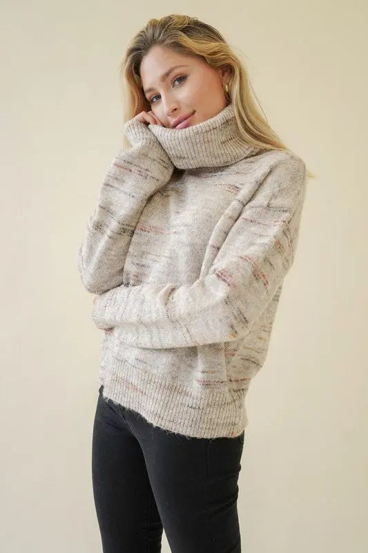 A female model showcasing a oatmeal textured turtleneck pullover sweater